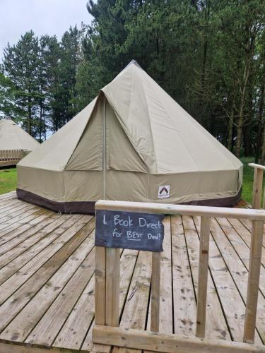 a large tent on a wooden deck with a sign at Swanns Bridge Glamping in Limavady