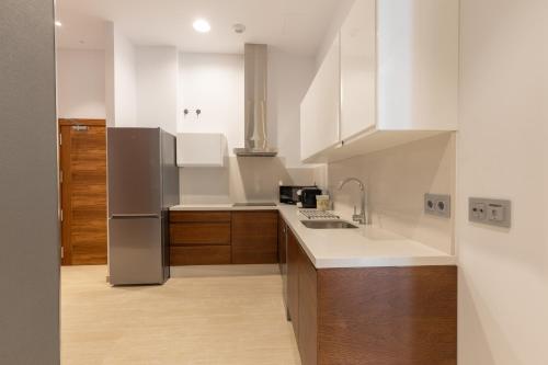 a kitchen with white cabinets and a stainless steel refrigerator at BiBo Suites San Agustín in Granada