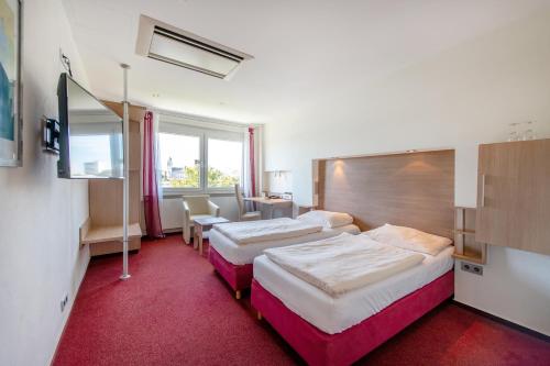 a hotel room with two beds and a television at Diehls Hotel in Koblenz