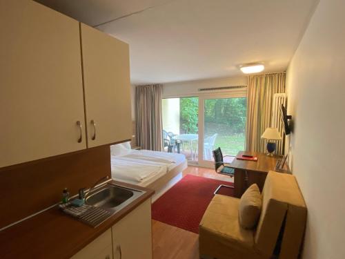 a room with a bed and a kitchen with a sink at Central Hotel-Apart München in Munich