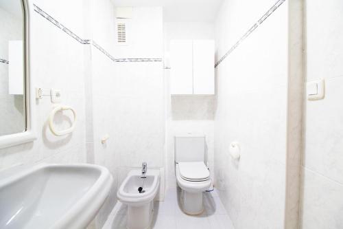 a white bathroom with a toilet and a sink at Global Properties, Apartamento con piscina en Residencial Brezo in Canet de Berenguer