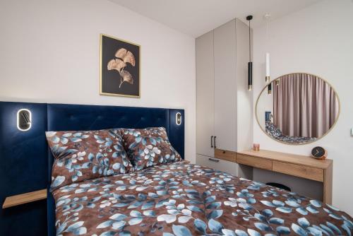 a bedroom with a blue bed and a mirror at Apartament Bursztynowy Władysławowo in Władysławowo