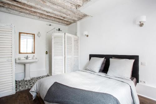 Habitación blanca con cama y lavabo en Appartement Gérard, tout équipé Paris 13éme, en París