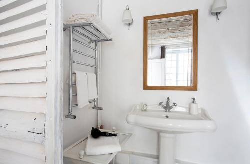 La salle de bains blanche est pourvue d'un lavabo et d'un miroir. dans l'établissement Appartement Gérard, tout équipé Paris 13éme, à Paris