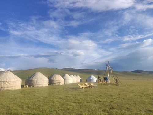 een groep koepels in een veld met een windmolen bij Yurt camp ALI-NUR at lake Song-Kol юрточный лагерь Али-Нур озеро Сон-Куль Сон-Куль Кыргызстан Нарын Kyrgyzstan Naryn in Naryn