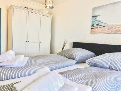 um quarto com 2 camas e um armário branco em Weitblick em Westerland