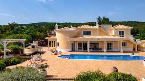 a large villa with a swimming pool in front of it at Casa do Pomar by Portucasa in Alte