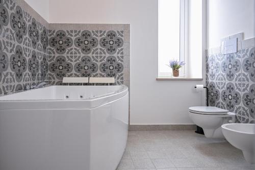 a bathroom with a tub and a toilet and a sink at Dimora Savarino Marzamemi Suites with pool in Marzamemi