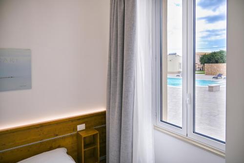 a bedroom with a window with a view of a pool at Dimora Savarino Marzamemi Suites with pool in Marzamemi
