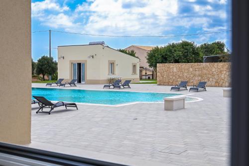 a swimming pool with chairs and a house at Dimora Savarino Marzamemi Suites with pool in Marzamemi