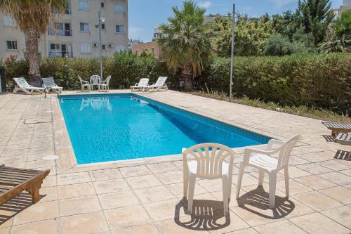 una piscina con 2 sillas, una mesa y sillas en Paphos Love Nest Apartment, en Pafos