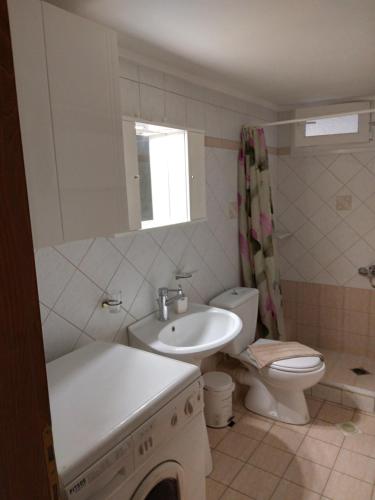 a white bathroom with a sink and a toilet at Central Fountain in Asprovalta