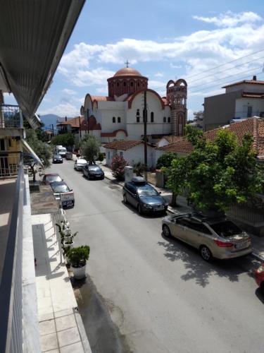 a street with cars parked in front of a building at Central Fountain in Asprovalta
