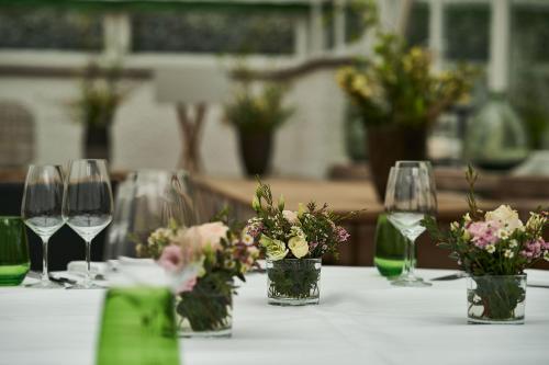 a table with wine glasses and flowers in vases at Relais & Châteaux Hardenberg BurgHotel in Nörten-Hardenberg