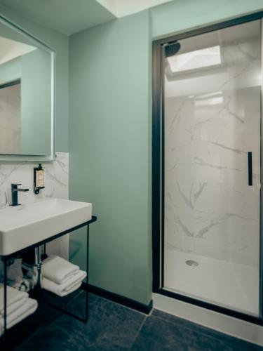 a bathroom with a sink and a glass shower at Le Nemours Rennes in Rennes