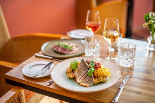 a table with a plate of food and glasses of wine at Diehls Hotel in Koblenz