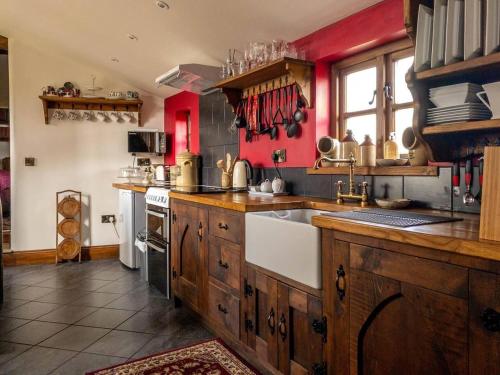 a large kitchen with wooden cabinets and red walls at Peak District Cottage set in 5 acres near Buxton in Buxton