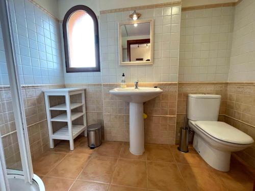 een badkamer met een wastafel, een toilet en een spiegel bij Sea view apartment with garden Mojon Hills in Isla Plana