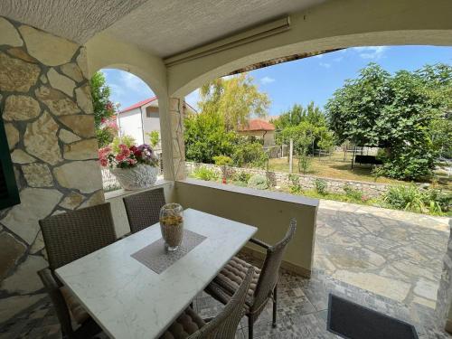 a porch with a table and chairs and a stone wall at Apartman Veronika in Vrsi