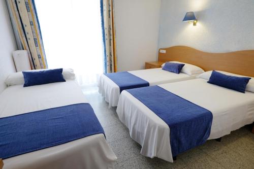 a hotel room with three beds with blue and white sheets at Hotel Internacional in Calella