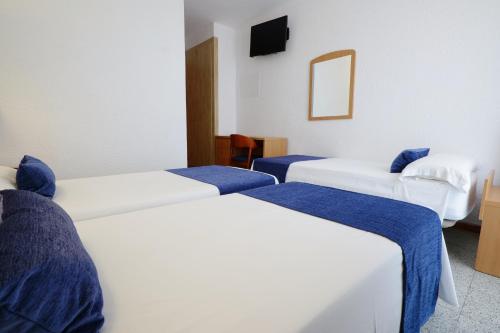 a room with two beds with blue sheets and a mirror at Hotel Internacional in Calella