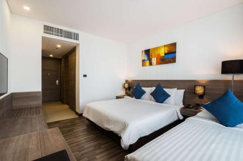 two beds in a hotel room with blue pillows at Best Western Plus Wanda Grand Hotel in Nonthaburi