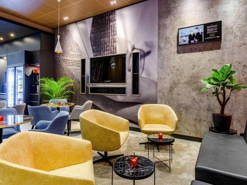 a waiting room with yellow chairs and tables and a tv at Ibis Berlin Hauptbahnhof in Berlin