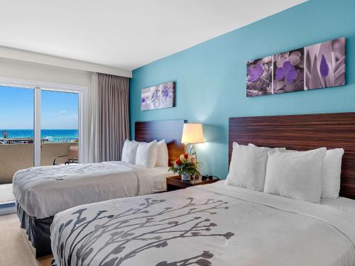 two beds in a hotel room with a view of the ocean at Sleep Inn on the Beach in Orange Beach