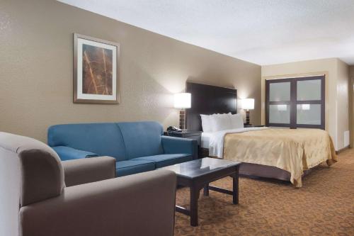 a hotel room with a bed and a blue couch at Quality Inn Magnolia in Magnolia