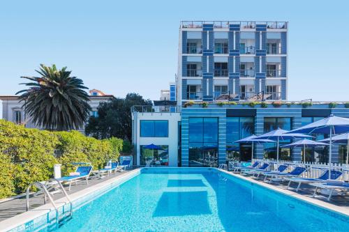 einen Pool mit Stühlen und Sonnenschirmen neben einem Gebäude in der Unterkunft Hotel Excelsior in Marina di Massa