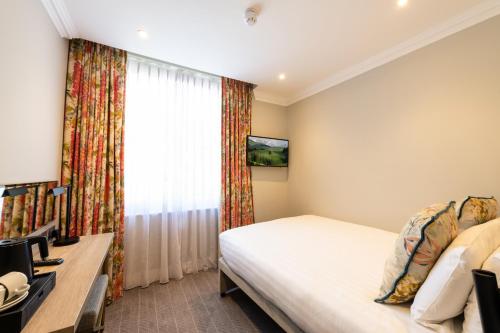 a bedroom with a bed and a desk and a window at Byron Hotel in London