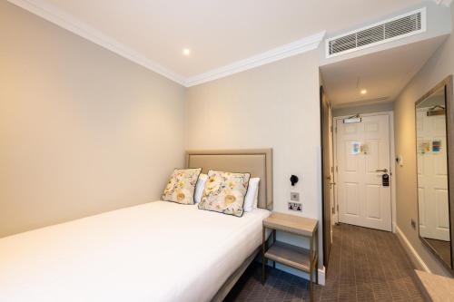 a bedroom with a white bed with two pillows at Byron Hotel in London
