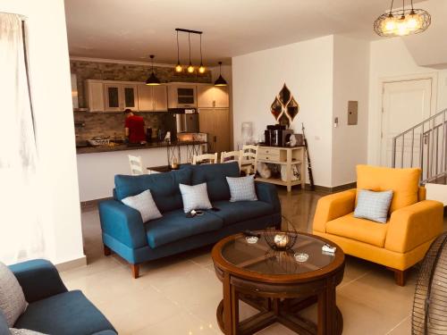 uma sala de estar com um sofá e duas cadeiras e uma mesa em Lovely chalet 4- bedroom directly on the lagoon em El Alamein