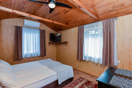 a bedroom with a bed with a ceiling fan and two windows at Namelio nuoma in Palanga