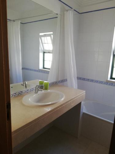 a bathroom with a sink and a mirror and a tub at Villa V2 U in Olhos de Água