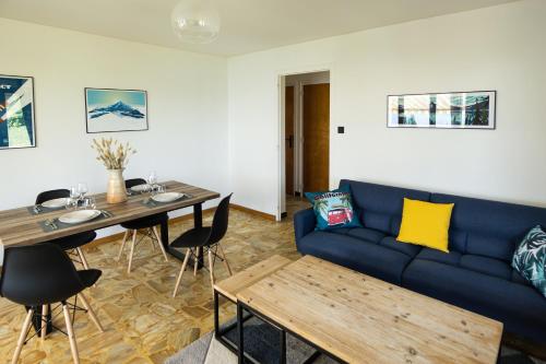 ein Wohnzimmer mit einem blauen Sofa und einem Tisch in der Unterkunft T3 avec vue imprenable sur le lac d'Annecy in Veyrier-du-Lac