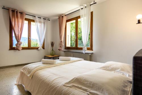 1 dormitorio con 1 cama blanca grande y ventanas en T3 avec vue imprenable sur le lac d'Annecy, en Veyrier-du-Lac