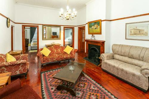 a living room with a couch and a fireplace at Ravenscliff Villa in Oudtshoorn