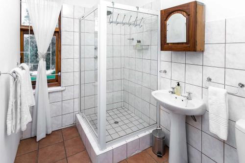 a white bathroom with a shower and a sink at Ravenscliff Villa in Oudtshoorn
