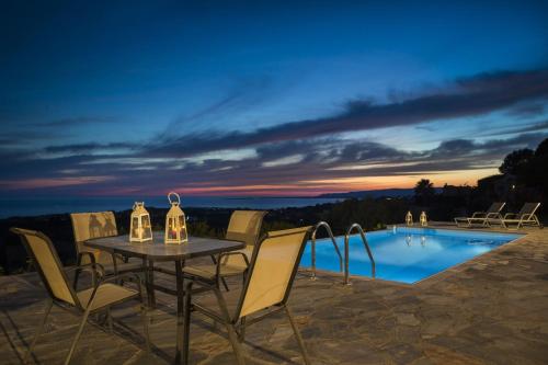 a table and chairs next to a pool at night at Villa Elaia in Svoronata