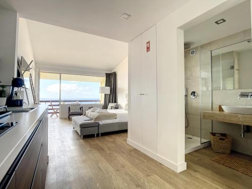 ein Schlafzimmer mit einem Bett und ein Badezimmer mit einem Waschbecken in der Unterkunft Madeira Ocean View by Atlantic Holiday in Caniço