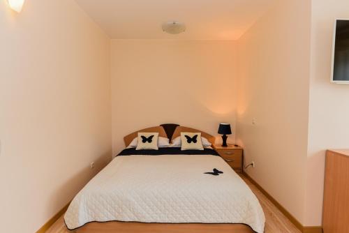 Schlafzimmer mit einem Bett mit weißer Bettwäsche und Kissen in der Unterkunft Apartamentų nuoma in Palanga