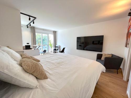 una camera da letto con un grande letto bianco e una televisione di le loft 56 de Boulogne a Boulogne-Billancourt