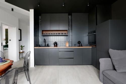 a kitchen with gray cabinets and a table and a couch at Partnerapart Rakowicka 14 Kamienica in Krakow
