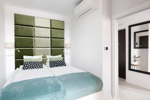 a bedroom with a large bed with a green headboard at Partnerapart Rakowicka 14 Kamienica in Krakow