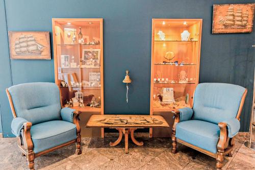 a room with two blue chairs and a table and shelves at Diehls Hotel in Koblenz