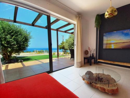 a living room with a red couch and a glass table at Seafront apartment with private garden in Saint Amvrosios