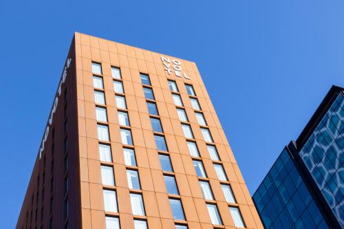 a tall orange building with a clock on it at Novotel Liverpool Paddington Village in Liverpool