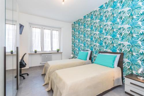 two beds in a room with blue wallpaper at La Casa di Ezio a pochi passi dal Centro in Turin