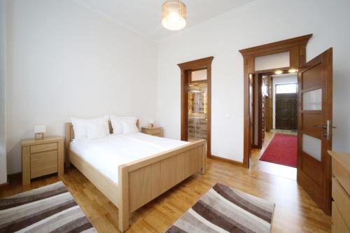 a bedroom with a large white bed and wooden floors at Virág Apartman Luxury in Odorheiu Secuiesc
